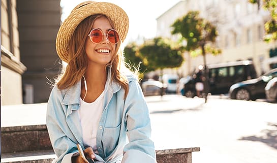woman with sunglasses and hat smiling