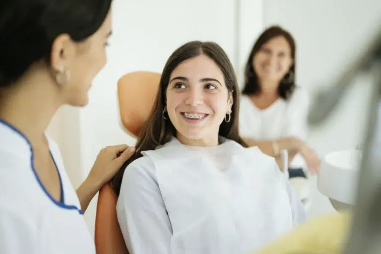Happy Teenage Patient Smiling At Female Dentist