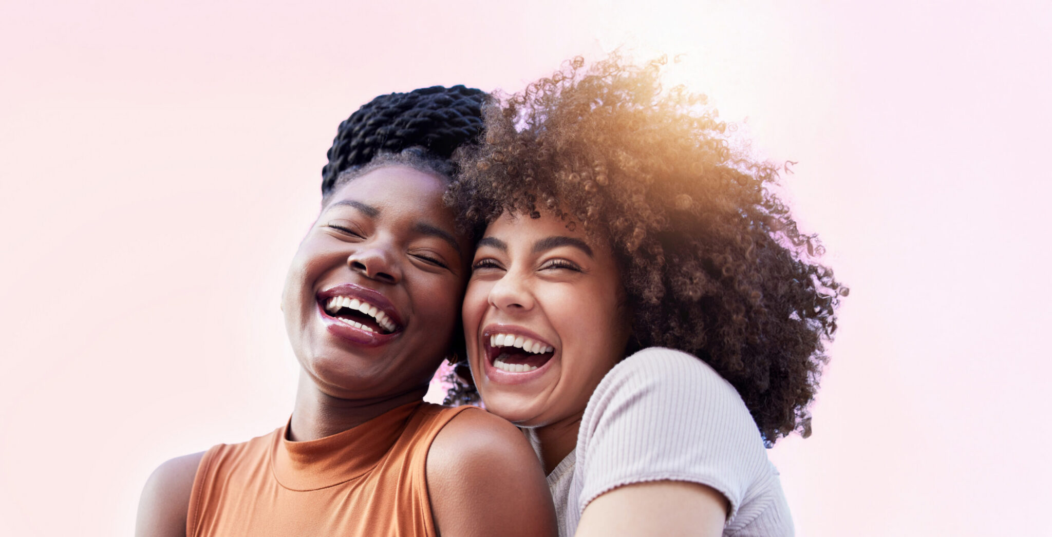 Two Women Hugging And Smiling In Sunlight